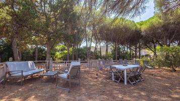 An outdoor patio with a dining table and chairs, surrounded by trees.