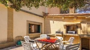 An outdoor patio with a round table, white chairs, and a grill. - La villa  des pins (Agde)