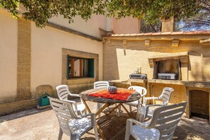 An outdoor patio with a round table, white chairs, and a grill. - La villa  des pins (Agde)