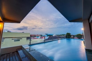 Una piscina en la azotea con vistas a edificios y un cielo al atardecer.