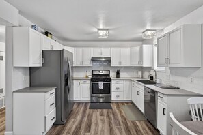 A modern kitchen with white cabinetry, stainless steel appliances, and a wooden floor. - Family-Friendly Tahoe Home w/ 2 Living Rooms, 3BR, Pack n Play, Near Heavenly Skiing (South Lake Tahoe)
