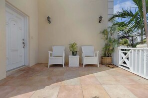 Eine Terrasse mit zwei weißen Stühlen, einem kleinen Tisch und einem Blumentopf.