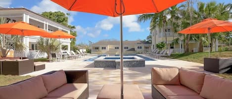 A pool area with outdoor seating and umbrellas.