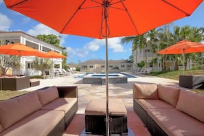 A pool area with outdoor seating and umbrellas.