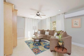A living room with a sofa, a coffee table, a ceiling fan, and a potted plant. - 4 BR w/ 6 Beds Near Atlantis (Nassau)