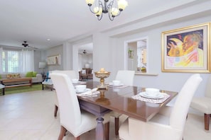 A dining area with a table set for four, white chairs, and a chandelier. - 4 BR w/ 6 Beds Near Atlantis (Nassau)