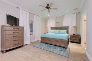A bedroom with a bed, a dresser, a television, a ceiling fan, and a window with curtains. - 4 BR w/ 6 Beds Near Atlantis (Nassau)