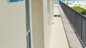 Ein Korridor mit einem Balkon mit Blick auf einen Strand, einem Schild mit der Zimmernummer 501 und freiem Blick auf den Ozean.