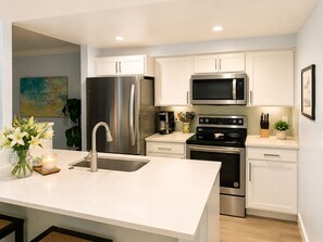 A modern kitchen with stainless steel appliances, a white countertop, and a sink. - Beautifully Remodeled Gulf View Condo on Sanibel Island (Sanibel)