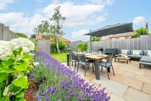 A patio with a table set for dining, outdoor seating, and a covered area. - Pebbles, Thornham, Norfolk (Thornham)