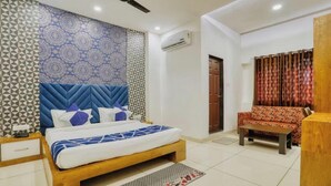 Un dormitorio con cama, mesita de noche, sofá, mesa de centro y ventilador de techo.