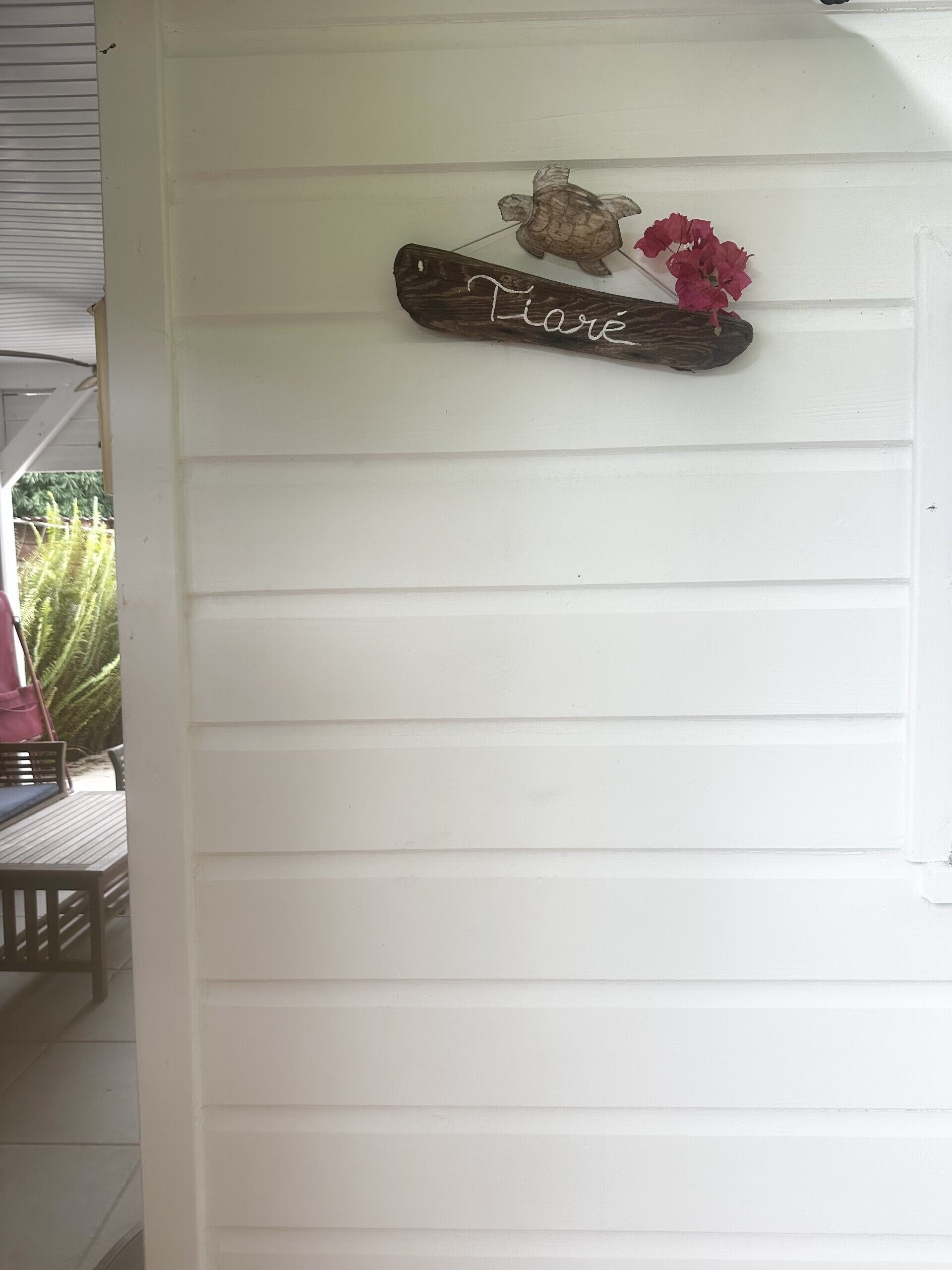 A white exterior wall with a wooden sign that reads 'Mare' and a small turtle figurine.