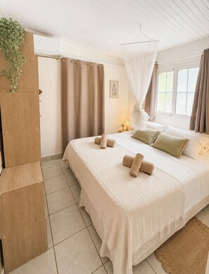 Ein Schlafzimmer mit Bett, Vorhängen, einer Nachttischlampe und einer hängenden Pflanze.