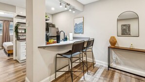 A modern kitchen with a bar area, a dining table with chairs, and a large mirror. - September Savings:15% Off All 3+ Night Stays! (Charlotte)
