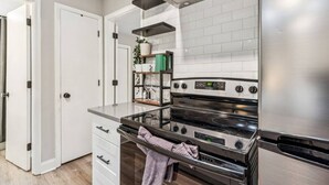 A modern kitchen with white cabinetry, a stainless steel range hood, and a built-in oven. - September Savings:15% Off All 3+ Night Stays! (Charlotte)