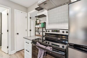 A modern kitchen with white cabinetry, a stainless steel range hood, and a built-in oven. - September Savings:15% Off All 3+ Night Stays! (Charlotte)