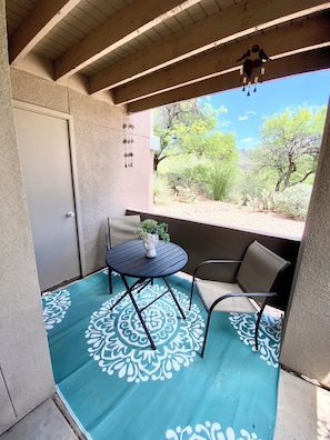A covered patio with a table and chairs, a hanging wind chime, and a view of desert vegetation. - Sweeping views of the Catalina Mountain from this corner 3 bedroom (Tucson)