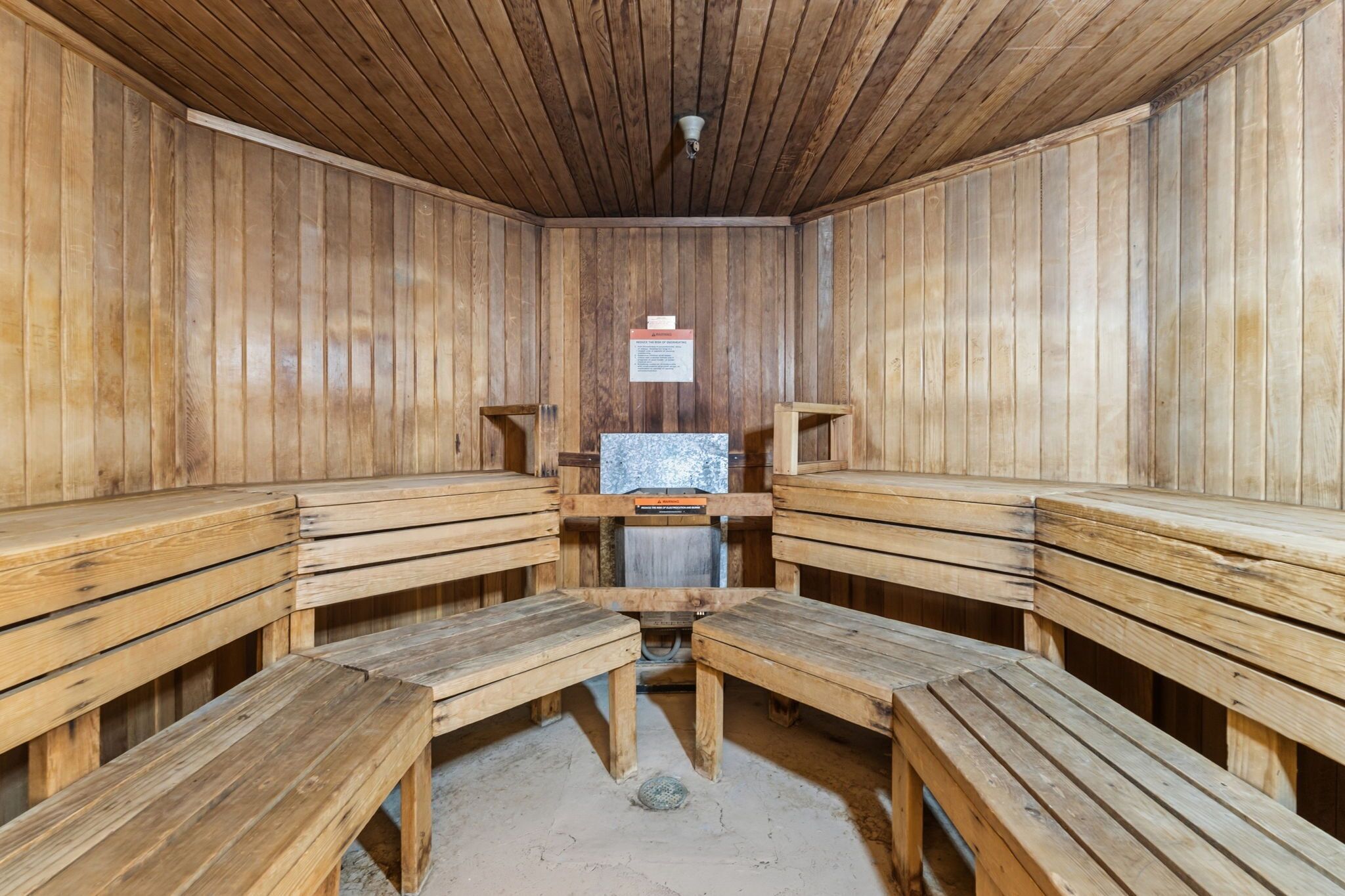 Un sauna avec des bancs en bois et un banc central.
