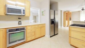 Una cocina moderna con electrodomésticos de acero inoxidable, armarios de madera y piso de baldosas.