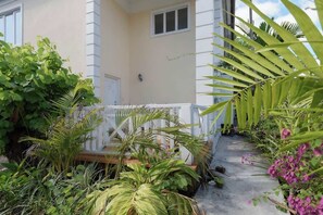 A house with a porch, surrounded by various plants and a concrete pathway. - 4 BR Villa w/ Unique Layout Perfect f/ Large Group (Nassau)