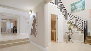Un interior amplio con una escalera, un comedor y un pasillo que conduce a un baño.