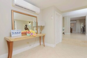A hotel lobby with a large mirror, a wooden console table with towels, and a sign reading 'LIFE'S A BEACH.' - 4 BR Villa w/ Unique Layout Perfect f/ Large Group (Nassau)