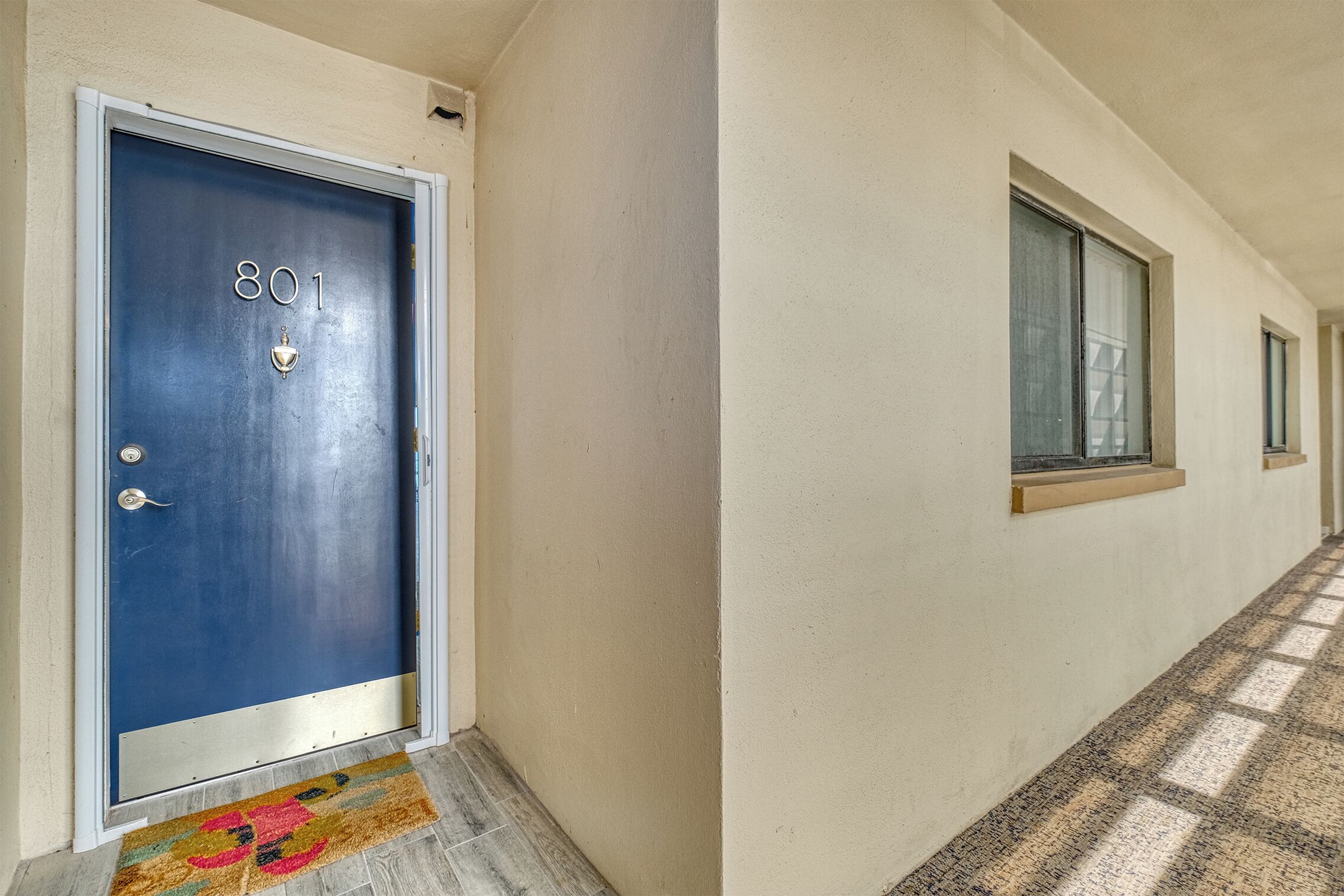 A hallway with a blue door marked '801' and a window with a wooden frame.