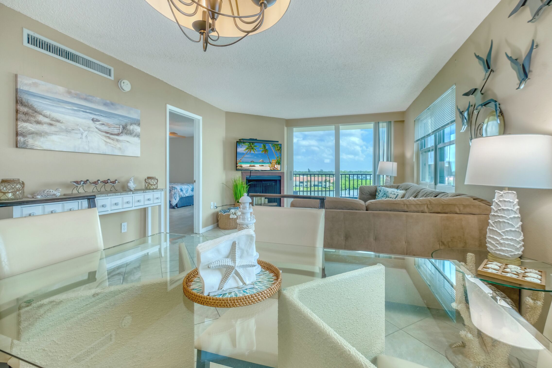 A spacious living room with a glass coffee table, a sofa, and a television.