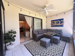 A modern outdoor seating area with a glass-top table, cushioned seating, a ceiling fan, and a patterned rug. - Sarasota Beach Escape Minutes to Sands & Sunsets (Sarasota)