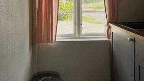 A small room with a window, a trash bin, and a cabinet. - Scanian longhouse with studio in Österlen (Smedstorp Tomelia)