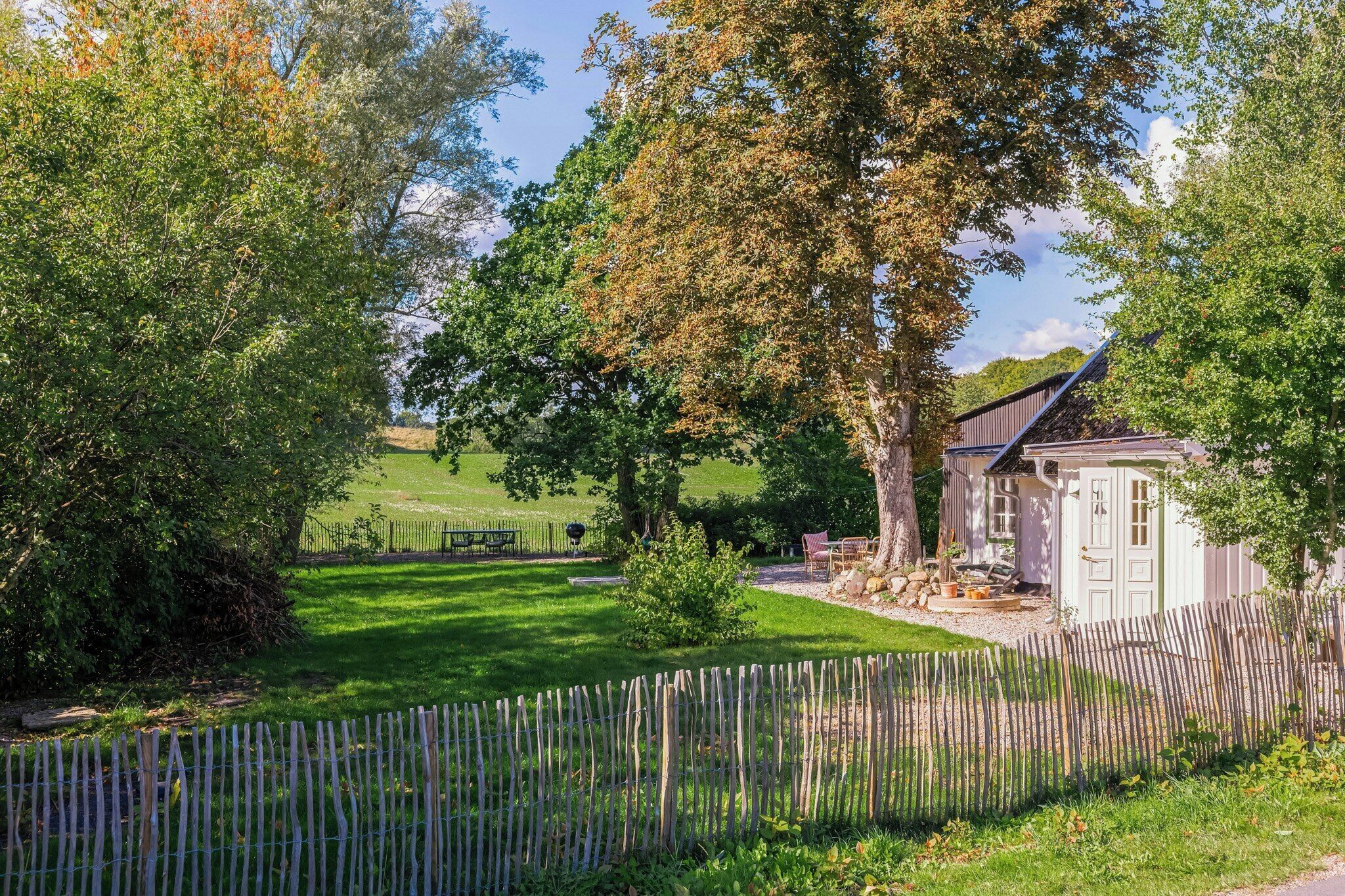 A rural property with a fenced yard, a small shed, and a large tree.