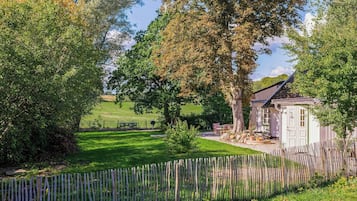 A rural property with a fenced yard, a small shed, and a large tree.