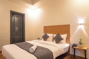 A hotel room with a bed, bedside table, and a door. - Hotel Silver Stay Classic (Jaipur)