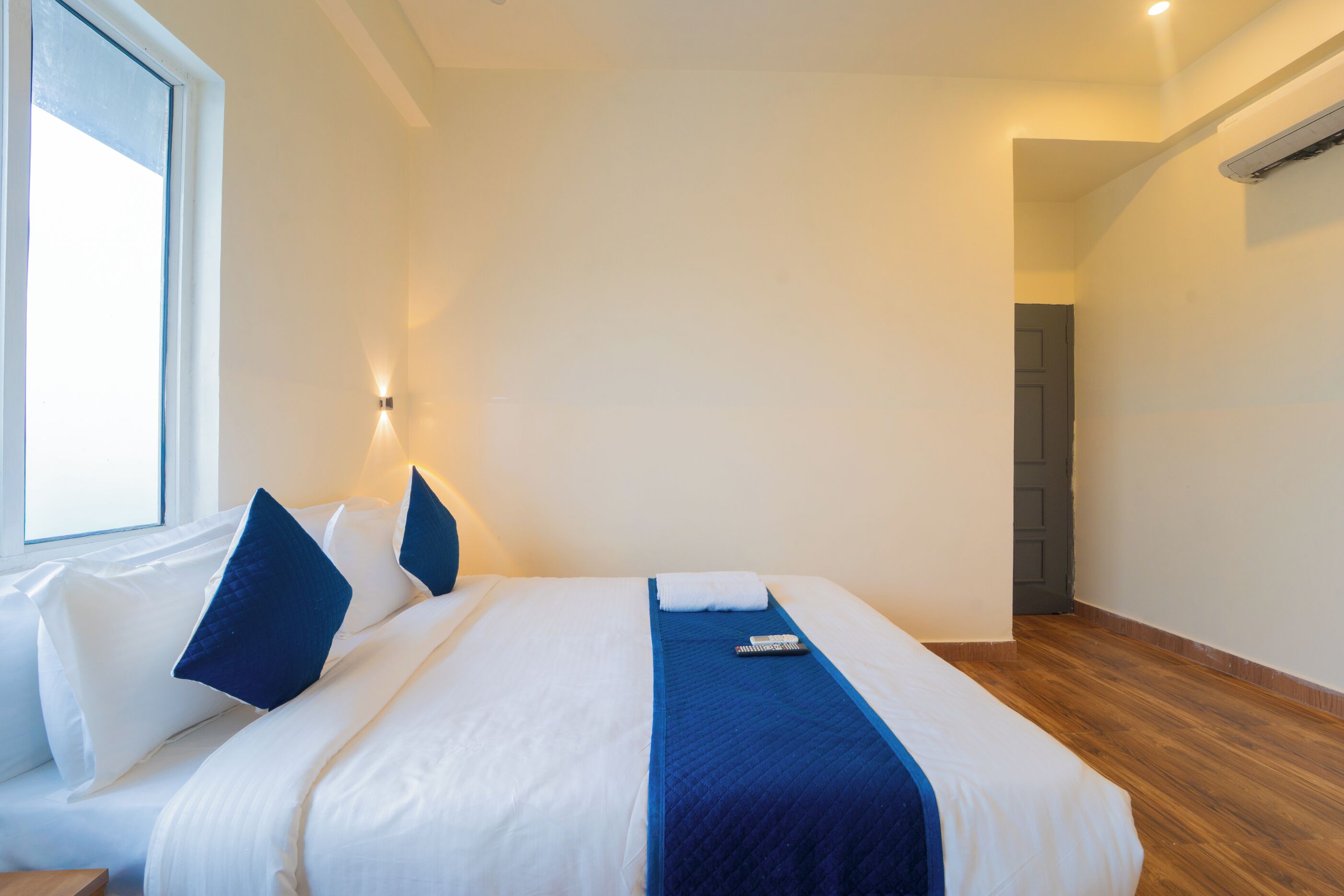 Quarto de hotel com uma cama grande, uma janela e uma porta.