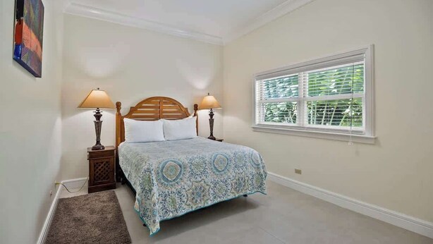 Quarto com cama, duas luminárias de cabeceira, janela com persianas e tapete.