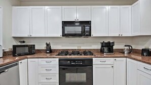 A kitchen with white cabinets, a microwave, stove, dishwasher, and coffee maker. - Comfortable Villa Near Beach + Atlantis + Downtown (Nassau)