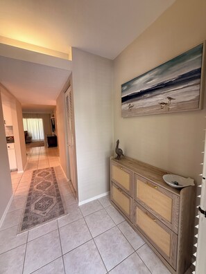 A hallway with a patterned rug, a wooden console with a sink, and a painting of birds on the wall. - Sarasota Beach Escape Minutes to Sands & Sunsets (Sarasota)