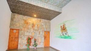 Una habitación con pared de piedra, puertas de madera y un mural.
