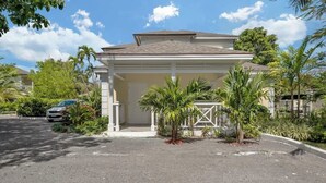 A two-story house with a covered porch, surrounded by palm trees and a clear sky. - Spacious Studio Near Atlantis Equipped w/ Kitchen (Nassau)