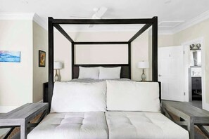 A four-poster bed with white bedding, a wooden headboard, and two bedside tables with lamps. - Silk Cotton Studio 1 (Nassau)