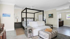 A bedroom with a four-poster bed, a desk, a chair, a small table, and a nightstand. - Silk Cotton Studio 2 (Nassau)