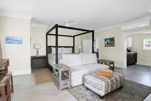 A bedroom with a four-poster bed, a desk, a chair, a small table, and a nightstand. - Silk Cotton Studio 3 (Nassau)