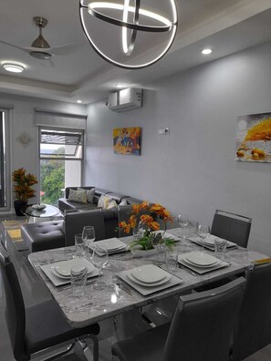 A modern dining area with a marble table set for four, surrounded by dark chairs. - 3BR Luxury Penthouse Suite - Dream 36  (Montego Bay)