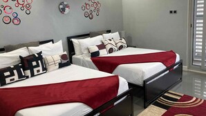 A hotel room with two beds, a red and white patterned rug, and wall decorations including a clock and abstract designs. - 3BR Luxury Penthouse Suite - Dream 36  (Montego Bay)