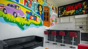 A modern lounge area with a colorful mural, a black sofa, red bar stools, and a coffee table. - 3BR Luxury Penthouse Suite - Dream 36  (Montego Bay)