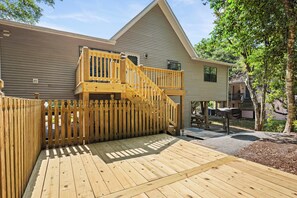 A wooden deck leading to a house with a balcony and a covered outdoor area. - 3BR Oceanside with Easy Beach Access | Golf cart + Pet Friendly (Emerald Isle)