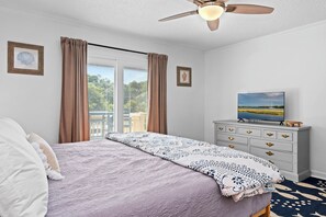 A bedroom with a bed, a dresser, a ceiling fan, and a window with curtains. - 3BR Oceanside with Easy Beach Access | Golf cart + Pet Friendly (Emerald Isle)