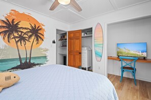 A bedroom with a bed, a desk with a chair, a television, and a wardrobe. - 3BR Oceanside with Easy Beach Access | Golf cart + Pet Friendly (Emerald Isle)