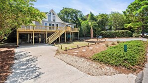 A two-story house with a covered porch and a staircase leading to the upper level. - Pet-Friendly Cottage w/ Golf Cart, Kayak & Easy Beach Access (Emerald Isle)