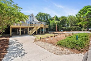 A two-story house with a covered porch and a staircase leading to the upper level. - Pet-Friendly Cottage w/ Golf Cart, Kayak & Easy Beach Access (Emerald Isle)